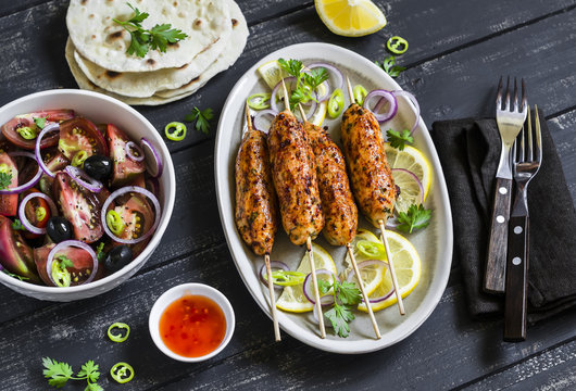 chicken kebab, salad with tomatoes, onions and olives, homemade tortilla is a healthy and delicious meal, on a dark wooden background