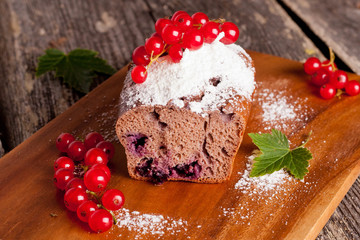 chocolate cake with red currant on wooden background, horizontal