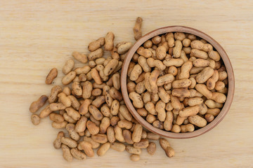 Roasted peanuts in wooden cup, top view.