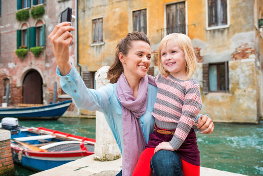 Happy mother and young daughter taking selfie in Venice