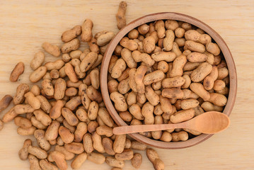 Roasted peanuts in wooden cup, top view.