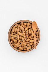 Roasted peanuts in wooden cup, top view isolated on white background.