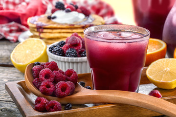juice of raspberries and blackberries with citrus and pancakes on the table