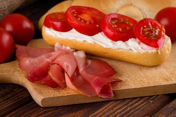 Slice of prosciutto ham on chopping board with fresh baguette
