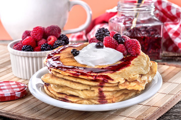 Pancakes with cream, raspberries and blackberries on the table