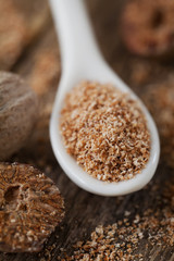 Nutmeg whole and grated on wooden background, selective focus