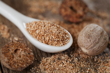 Nutmeg whole and grated on wooden background, selective focus