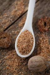 Nutmeg whole and grated on wooden background, selective focus
