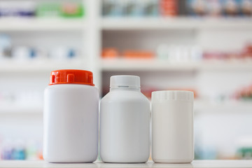 Blank white medicine bottles with blur shelves of drug in the ph
