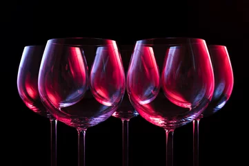 Printed roller blinds Wine Wine glasses lit by red, blue, lilac nightclub party lights on black background 