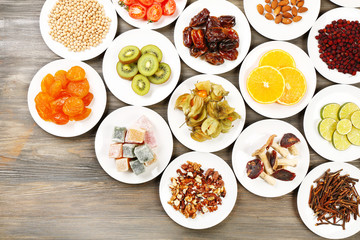 Different products on saucers on wooden table, top view