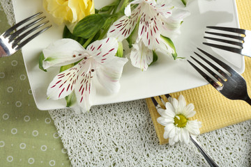 Tableware with flowers on table close up
