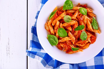 Pasta with tomato sauce and basil on table close up