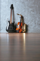 Electric guitar, saxophone and violin on gray wall background