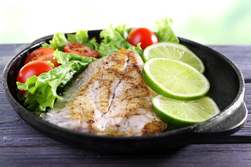 Dish of fish fillet with salad and lime on table close up