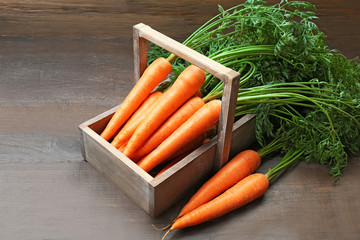 Fresh organic carrots in crate on wooden background