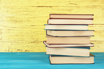 Stack of books on yellow wooden background