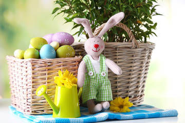 Easter bunny with painted Easter eggs with flowers on bright background