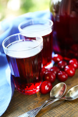 Sweet homemade cherry compote on table on wooden table, on bright background