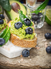 Sandwiches with avocado, blueberries and spinach on a dark grain bread
