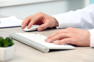 Doctor working at table in office