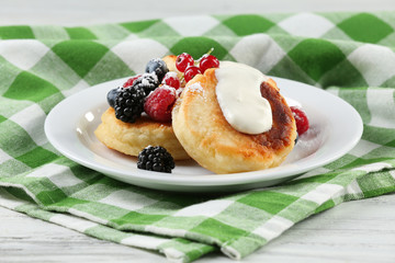 Fritters of cottage cheese with berries in plate, closeup