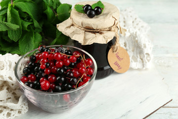 Ripe forest berries in glass bowl on light background