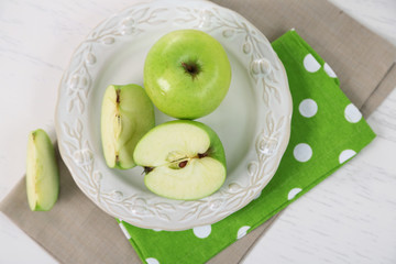 Green apples in plate on table with napkin, closeup