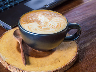 Laptop with latte art coffee cup on old wooden table