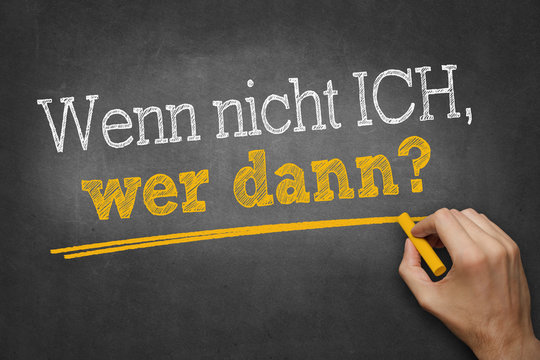 Hand schreibt mit Kreide Text "Wenn nicht ich, wer dann?" auf Tafel