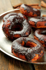 Delicious doughnuts with chocolate icing on metal tray close up