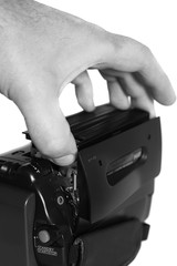 Video camera cassette loading.
Man loading a cassette into a video camera.