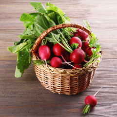 Fresh radishes in basket on wooden background