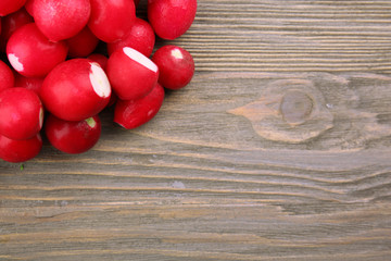 Heap of fresh radishes on wooden table close up background