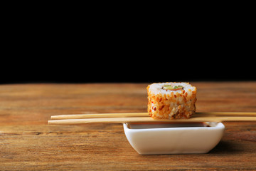 Roll with sauce and wooden sticks on dark background