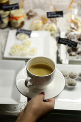 Fototapeta na wymiar Female hand holding cup of coffee on table background