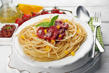 Spaghetti with tomato sauce and cheese on white plate, on color wooden background