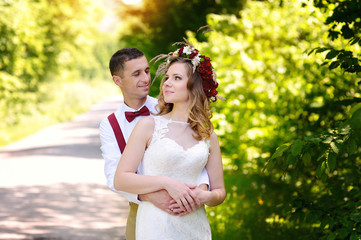 Obraz premium happy beautiful bride and groom walking on field in sunlight