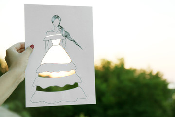 Female hand holding fashion sketch outdoors