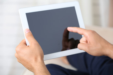 Male hand holding PC tablet on home interior background