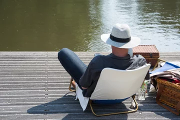 Foto auf Leinwand Man relaxt aan de waterkant op een steiger met smartphone © kokandkok