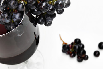 Red wine glass with grape within and berries isolated on white background