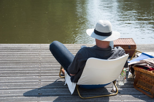 Man relaxt aan de waterkant op een steiger met smartphone