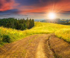 road on hillside meadow in mountain at sunset