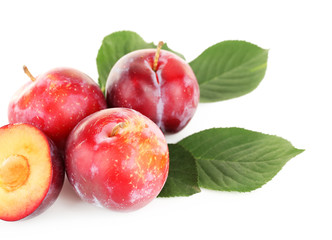 Ripe plums with green leaves isolated on white