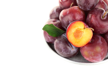Ripe plums in metal plate isolated on white