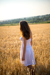 girl in a field looking at sunset