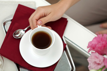 Female hand holding cup of tea on table close up