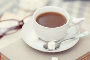 Cup of coffee with books on sofa in living room