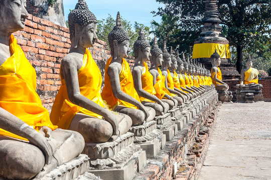 The prospect of a number of statues of seated Buddha, Thailand. Statues in yellow festive decoration. Bright sunny day.